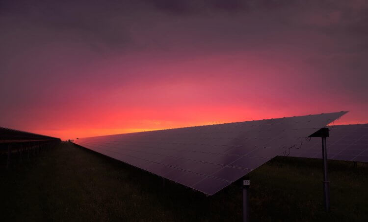 sunset behind row of commercial solar panels